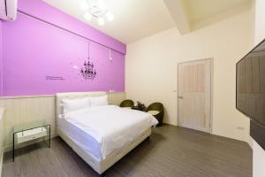 una camera con un grande letto con una parete viola di Iwaiker B&B a Città di Hualien