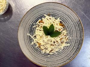 a bowl of food with cheese and a green leaf at Pensiunea Rusticanna Rinca in Ranca
