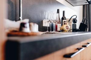 a kitchen counter with wine glasses and wine bottles at Clofers Relax Residences Rattendorf in Rattendorf