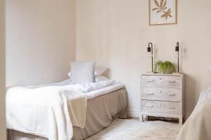 a white bedroom with a bed and a dresser at Cozy studio in separate building in Visby