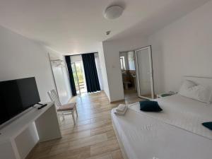 a white room with a bed and a flat screen tv at Pensiunea La Miluta in Caraorman
