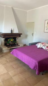 a bedroom with a purple bed and a fireplace at La Casa del Tau a Campigliano in Apoleggia