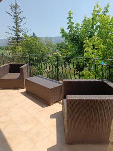 un patio con sillas de mimbre y mesas en un balcón en Véritable maison de campagne nouvellement rénovée au pied du Lubéron, en Cheval Blanc
