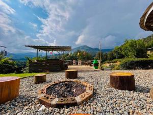 a fire pit with four logs on a gravel ground at Rakkhao Inthanon sunset view in Ban Yang Di Pha Mop