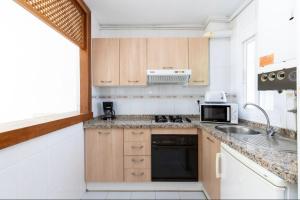 a kitchen with wooden cabinets and a sink at Apartamento en Golf Center Pueblo in Roquetas de Mar
