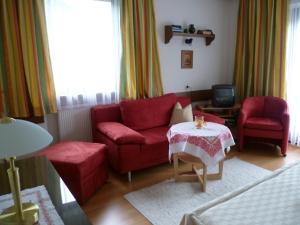 a living room with a red couch and two chairs at Haus Stadler in Sankt Gilgen