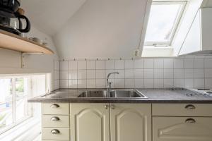 a kitchen with a sink and two windows at Cozy apartment in the middle of Visby town in Visby +13 photos