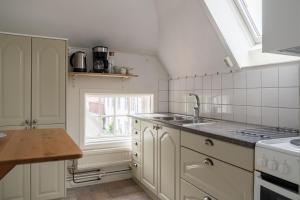 a white kitchen with a sink and a window at Cozy apartment in the middle of Visby town in Visby