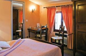 a bedroom with a bed and a desk and a mirror at Logis Hôtel Restaurant Les Géraniums in Le Barroux