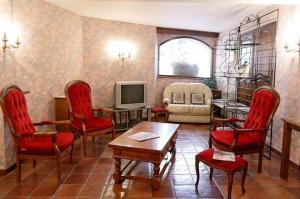 a living room with red chairs and a television at Logis Hôtel Restaurant Les Géraniums in Le Barroux
