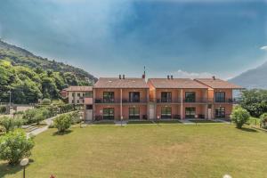 a large building with a large yard in front of a mountain at Monolocale con soppalco Brezza del lario by Varenna Holidays in Dervio