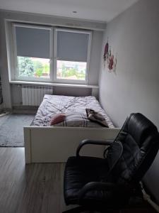 a small bedroom with a bed and a chair at Pokoje do wynajęcia in Michałowo