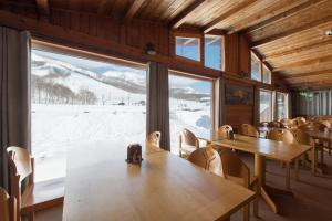 a restaurant with tables and chairs and a large window at Moiwa Lodge in Niseko