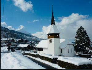 a white church with a steeple in the snow at Villa Lakeview Appartment in Leissigen +7 photos