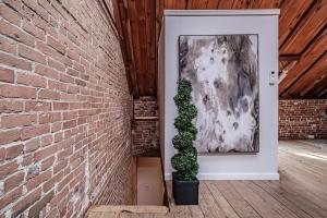 a brick wall with a painting and a potted plant at Lofty Ambition - Stunning West End Rooftop Retreat in Portland