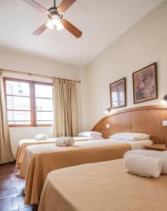 Habitación de hotel con 3 camas y ventilador de techo. en Argentino Hotel, en Mar del Plata