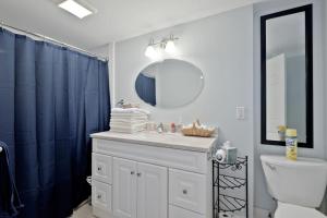 a bathroom with a sink and a blue shower curtain at Back Cove - Large Sunny 2 Bedroom Condo in Portland +42 photos