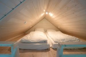 a room with two beds in a wooden attic at UMILI Pod Cyprysami - surf & family resort in Jastarnia