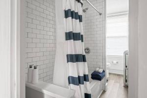 a bathroom with a black and white shower curtain at Skyline 138 Charming West End Mansard Penthouse in Portland +17 photos