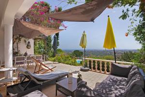 een patio met stoelen en een tafel en een gele parasol bij Villa La Ribeyre in Boliqueime