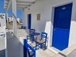 a blue door on a house with chairs and a table at Katerina Yalos in Ios Chora
