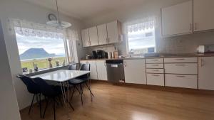 a kitchen with white cabinets and a table and chairs at Grund í Grundarfirði Economy Guesthouse in Grundarfjordur