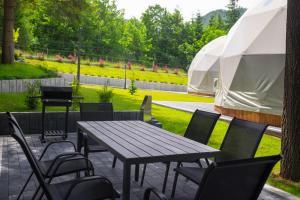 a patio with a table and chairs and a tent at Glamp Mała Łąka Jacuzzi & Sauna Zakopane in Zakopane