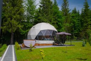 a dome tent in a garden with a table and an umbrella at Glamp Mała Łąka Jacuzzi & Sauna Zakopane in Zakopane