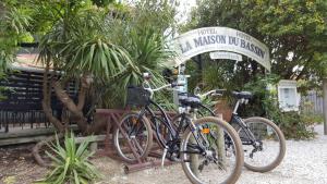 dwa rowery zaparkowane obok tabliczki w ogrodzie w obiekcie La Maison du Bassin w mieście Cap-Ferret