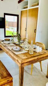 a wooden table with plates and wine glasses on it at Villa Salinas Beach Home Natural Park in La Manga del Mar Menor