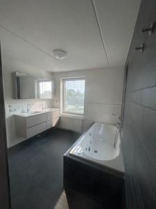 ザルトボメルにあるVakantievilla De Ketelの浴槽と洗面台のある白いバスルーム