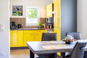 a kitchen with yellow cabinets and a table with chairs at Premiumferienhaus Vanua in Hasselfelde +29 photos