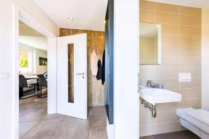 a bathroom with a white door and a sink at Premiumferienhaus Vanua in Hasselfelde