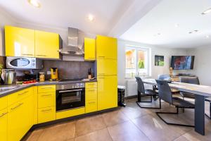 a kitchen with yellow cabinets and a table with chairs at Premiumferienhaus Vanua in Hasselfelde
