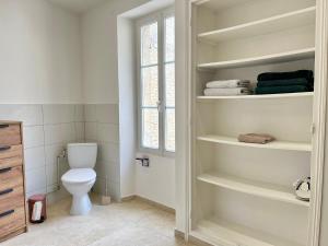 a bathroom with a toilet and towels on shelves at La Belle des champs - maison avec terrasse in Courseulles-sur-Mer +36 photos