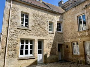 an old brick building with white doors and windows at La Belle des champs - maison avec terrasse in Courseulles-sur-Mer