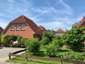 a house with a fence in front of it at Ferienhaus Maren in Nessmersiel an der Nordsee - hochwertig und gemütlich in Dornum