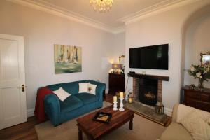 a living room with a blue couch and a fireplace at Chertsey Mount Townhouse, Carlisle in Carlisle