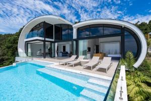 a modern house with a swimming pool and chairs at Seaview Dream Villa in Chaweng Noi Beach