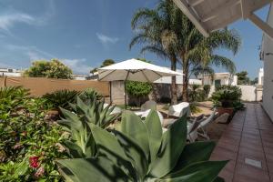 un patio con ombrellone, sedie e piante di Villetta al mare a Marina di Mancaversa