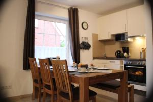 a kitchen with a wooden table with chairs and a dining room at Ferienhaus Maren in Nessmersiel an der Nordsee - hochwertig und gemütlich in Dornum