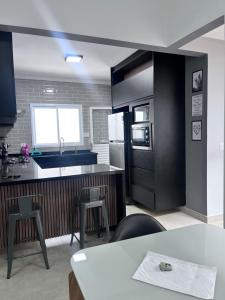 a kitchen with a sink and a counter with chairs at Casa aconchegante no interior in Boituva