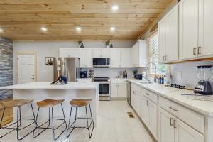 a kitchen with white cabinets and a counter with stools at Sweet Retreat in Sevierville