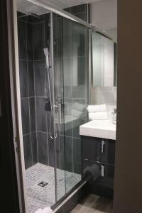 une salle de bain avec une douche en verre et un lavabo dans l'établissement Hôtel - Restaurant Eugenie, à Pontorson