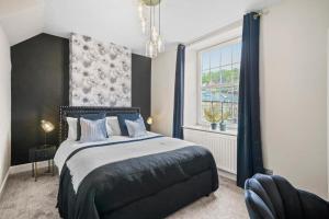 a bedroom with a bed with blue pillows and a window at New! - The Most Central and Lux Whitby House - Hot-Tub in Whitby