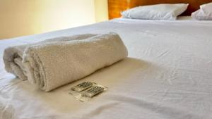 a towel laying on top of a white bed at 600m da UFV e 100m da rodoviária in Viçosa
