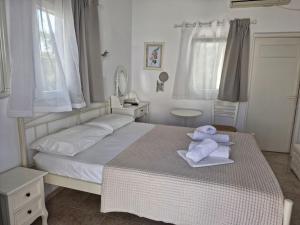 a white bedroom with a bed with towels on it at Katerina Yalos in Ios Chora