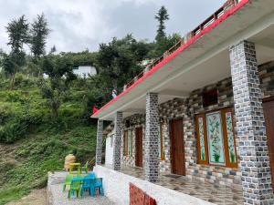 a house with chairs and tables on the side of it at Ganga Valley Homestay in Chakrāta