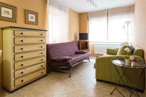 a living room with a dresser and a chair at Apartamentos Cotiello in Llanes