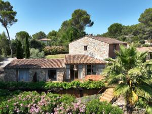 a stone house with a palm tree and flowers at LES TERRASSES DE LORGUES - B&B de charme en Provence in Lorgues